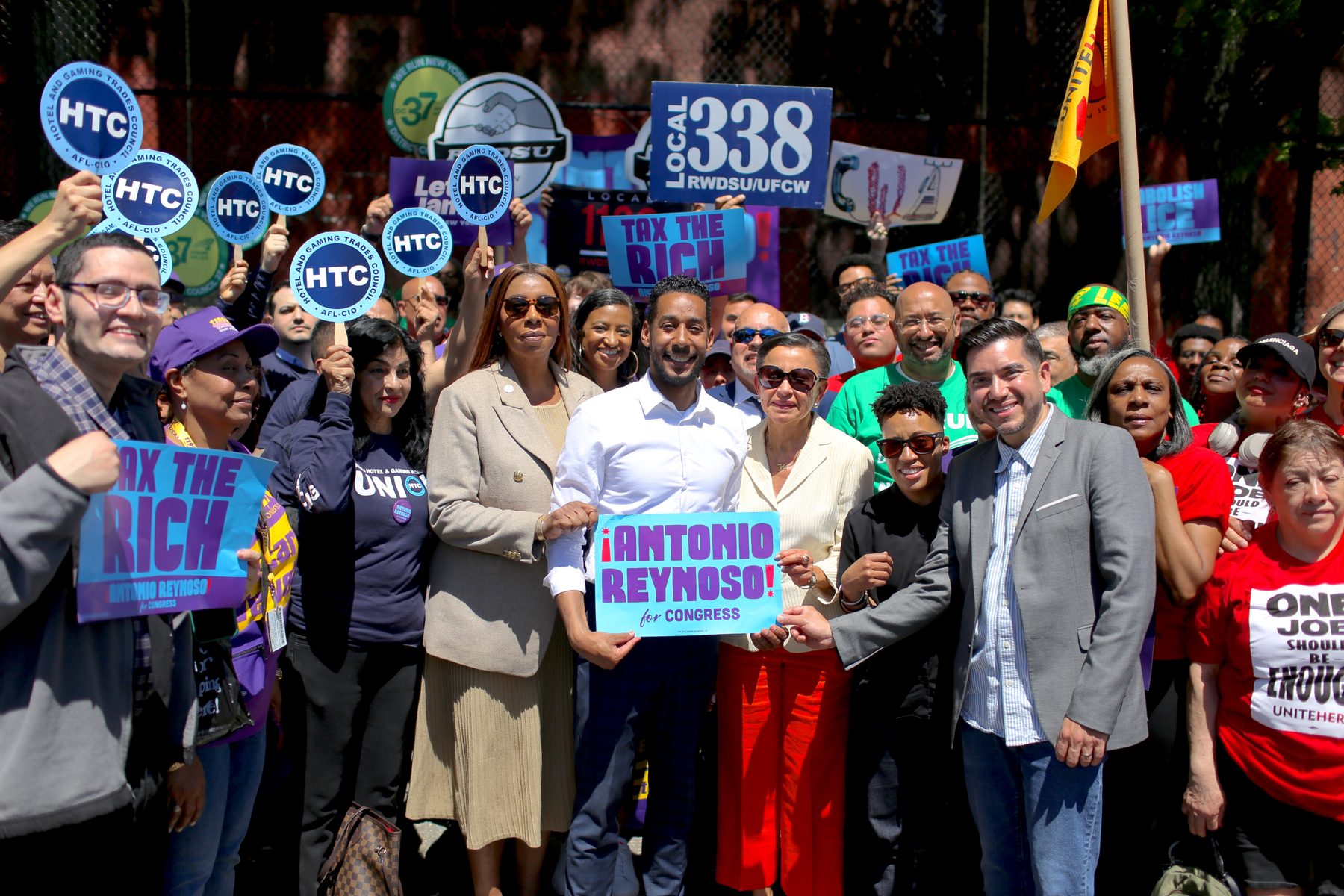 A crowd of union members and supporters at a rally holding signs, including 'Tax the Rich' and 'Antonio Reynoso for Congress'